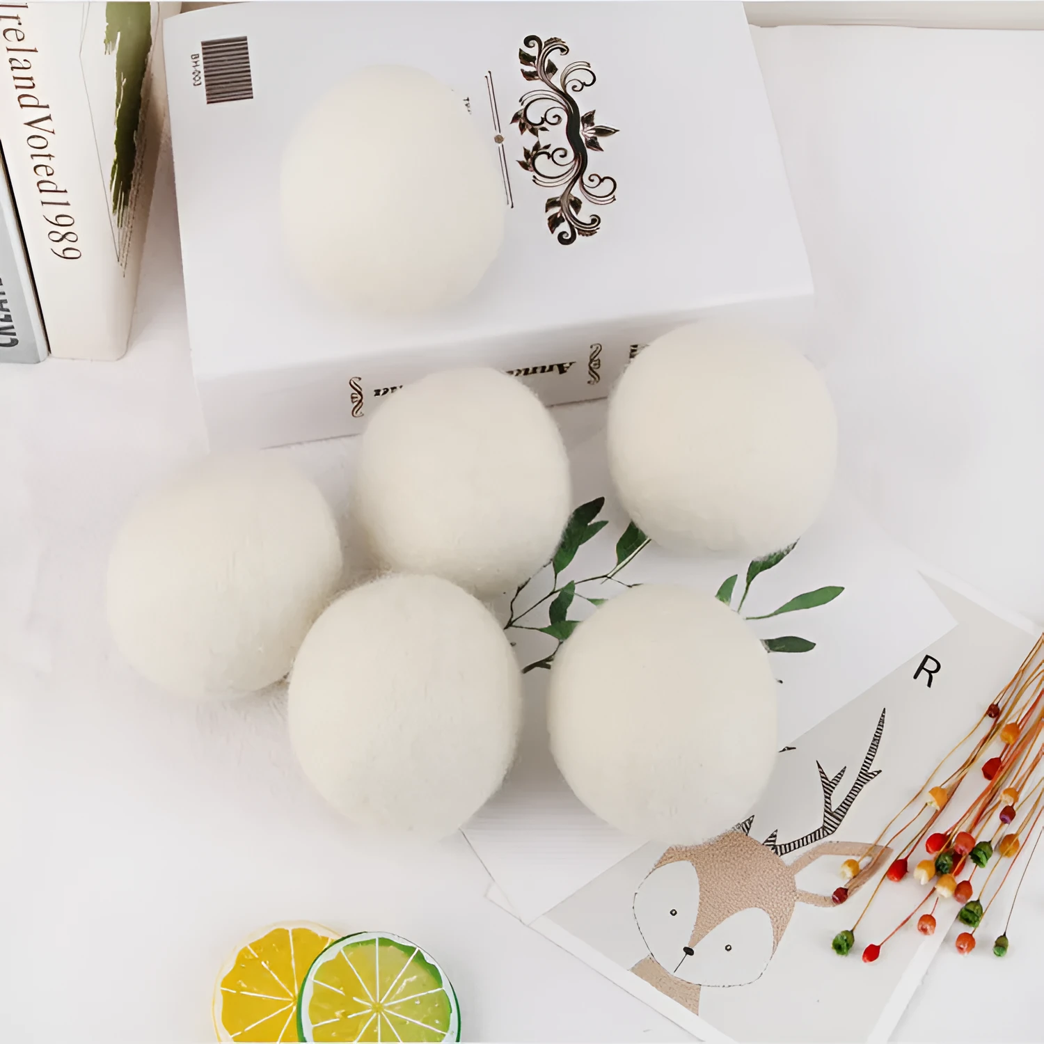 Natural wool laundry drying balls in various sizes next to plain cotton storage bag