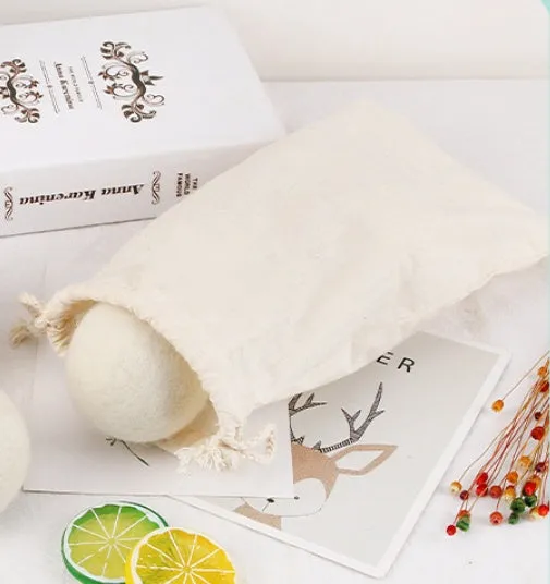 Natural wool laundry drying balls in various sizes next to plain cotton storage bag