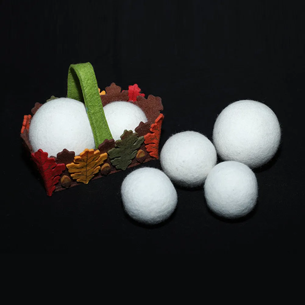 Natural wool laundry drying balls in various sizes next to plain cotton storage bag
