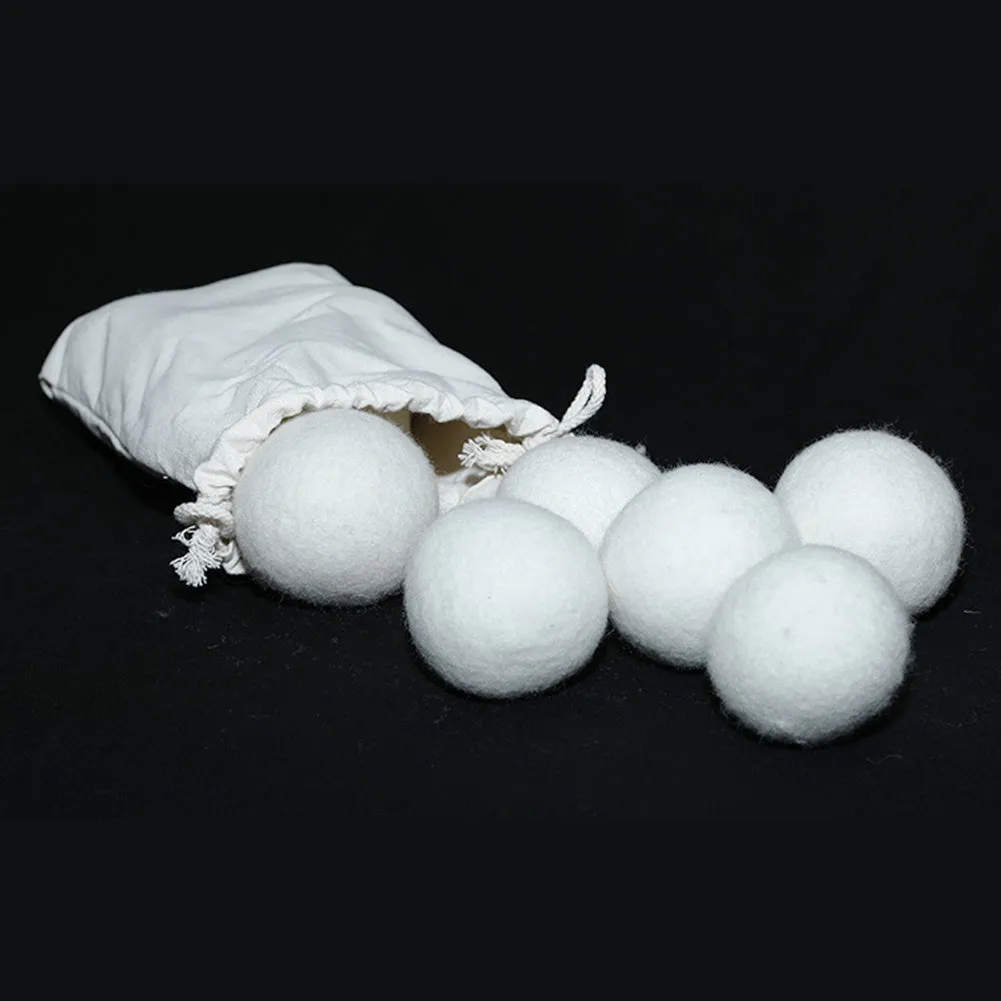 Natural wool laundry drying balls in various sizes next to plain cotton storage bag