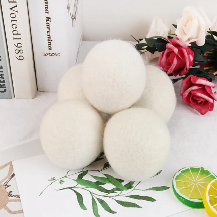 Natural wool laundry drying balls in various sizes next to plain cotton storage bag