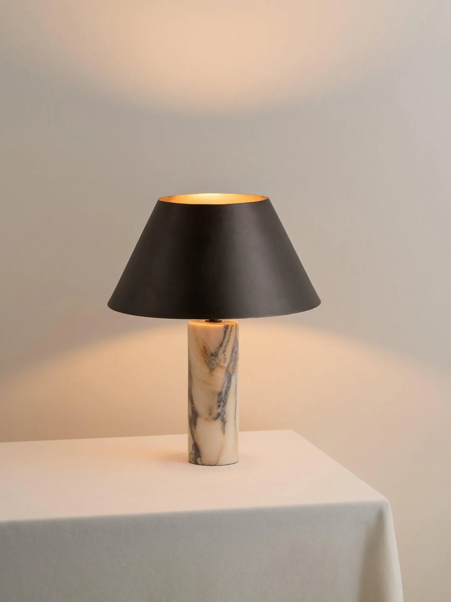 Modern black table lamp with a textured marble base on a wooden desk.