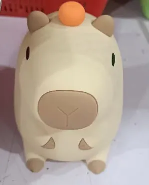 Cute brown Capybara silicone night lamp with soft glow on a bedside table.