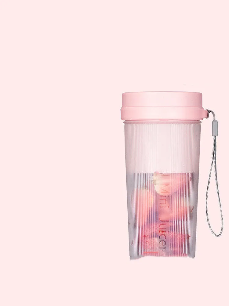 Portable pink and green rechargeable electric juicer cup with USB charging cable.