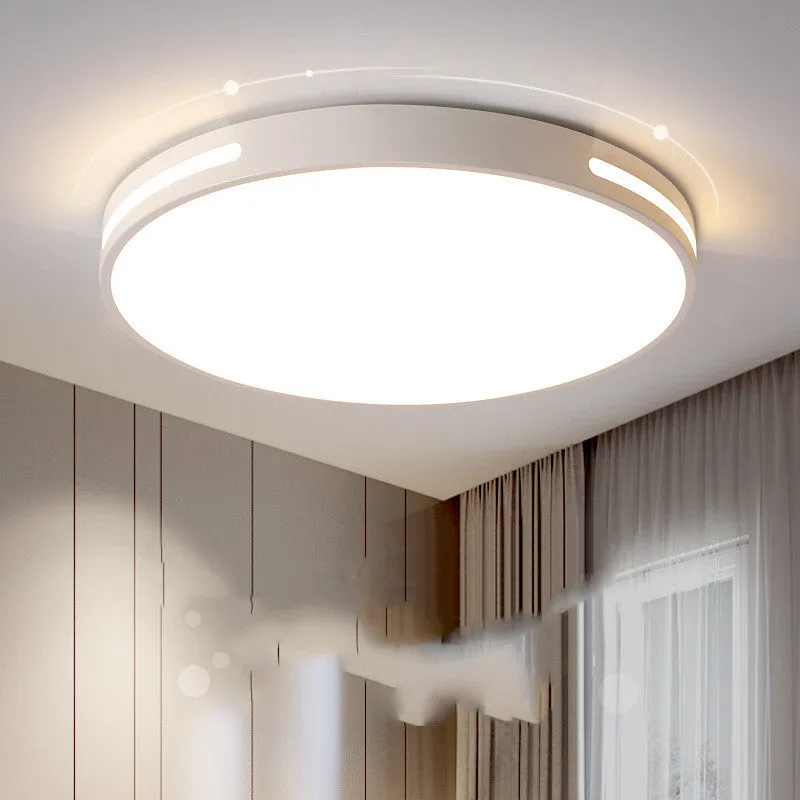 Round white acrylic remote control LED ceiling lamp mounted on a bedroom ceiling.