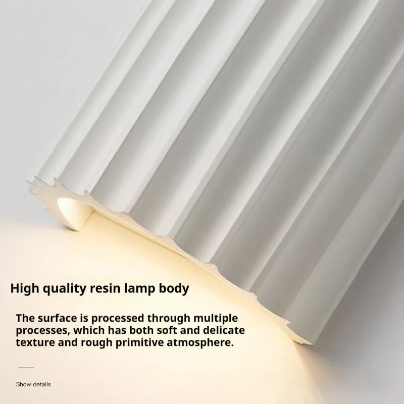 Nordic style wall light with a white macaron shell-shaped shade mounted on a hallway wall.
