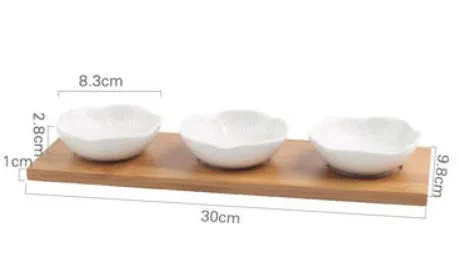 Porcelain ceramic dried fruit dish with three snack compartments on a wooden serving board.