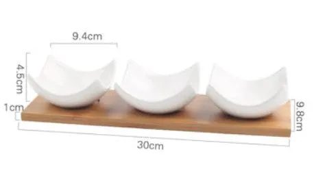 Porcelain ceramic dried fruit dish with three snack compartments on a wooden serving board.
