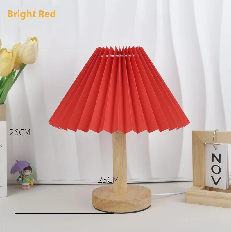 Vintage red pleated umbrella-shaped bedside lamp with remote control on a wooden nightstand.