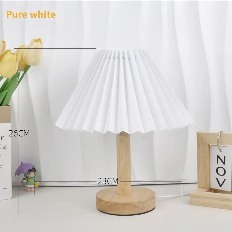 Vintage red pleated umbrella-shaped bedside lamp with remote control on a wooden nightstand.