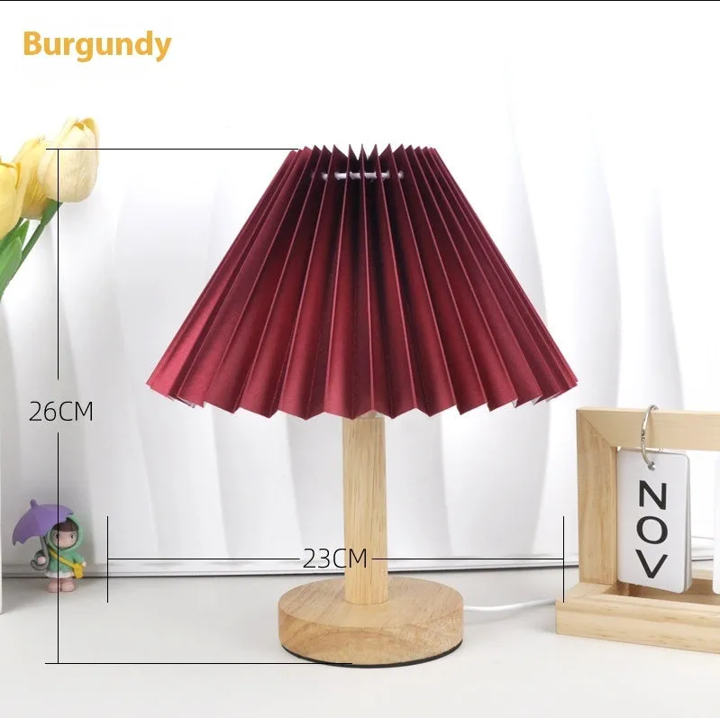 Vintage red pleated umbrella-shaped bedside lamp with remote control on a wooden nightstand.