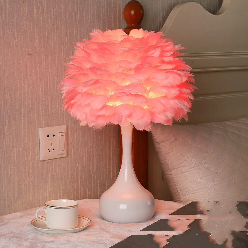 White feather table lamp with hand-woven fur shade and iron base on a wooden bedside table.