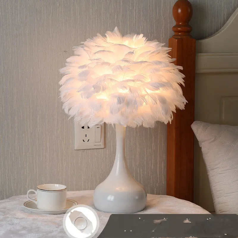 White feather table lamp with hand-woven fur shade and iron base on a wooden bedside table.
