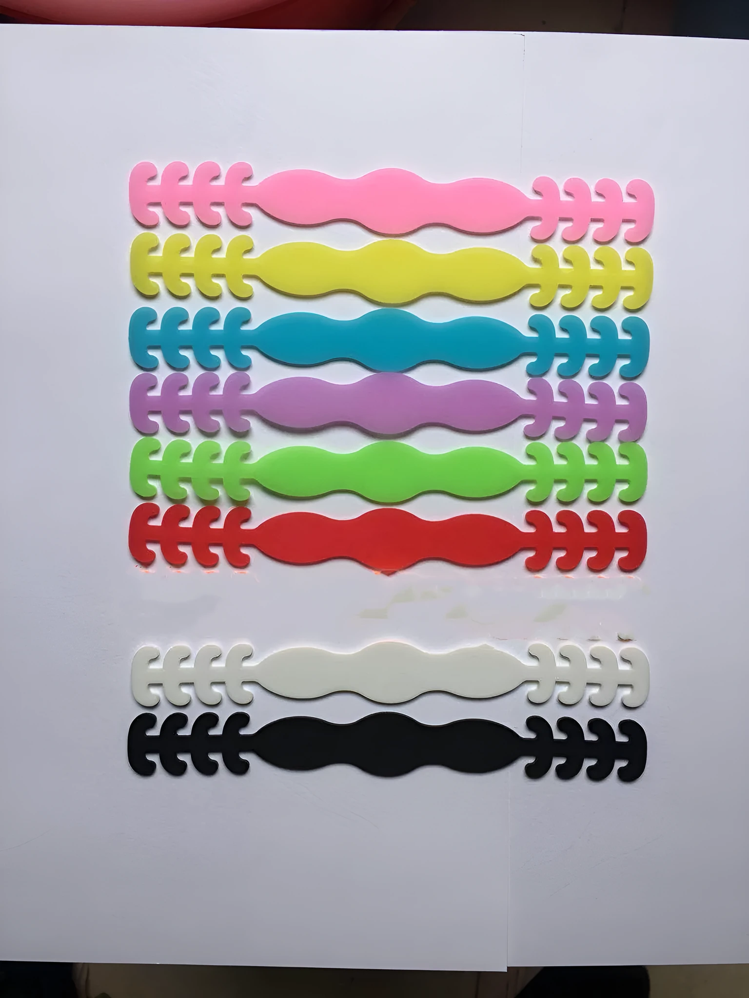 Pack of eight coloured silicone tool buckle straps on a workbench