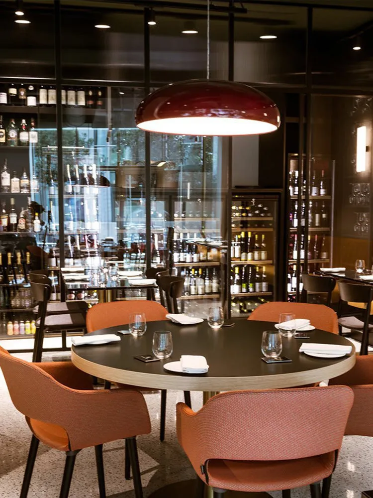 Danish iron pendant lamp in orange with adjustable cable hanging over a restaurant table.