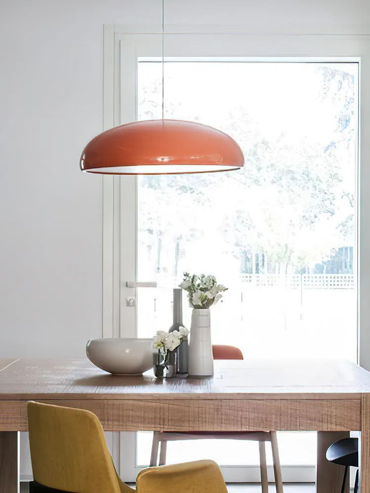 Danish iron pendant lamp in orange with adjustable cable hanging over a restaurant table.
