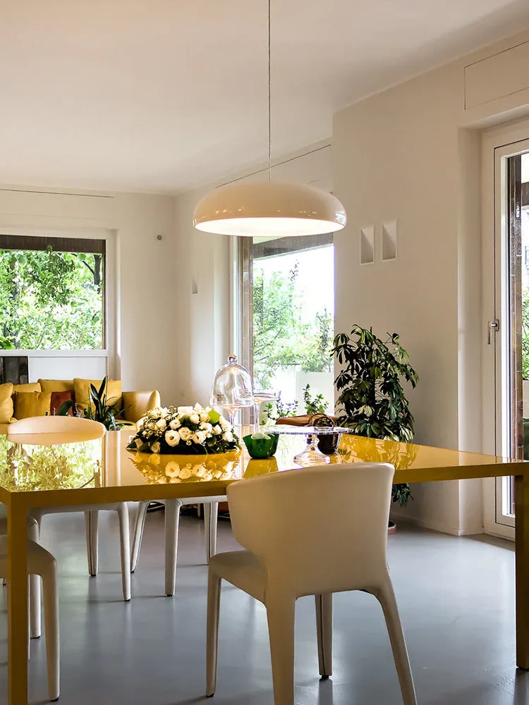 Danish iron pendant lamp in orange with adjustable cable hanging over a restaurant table.