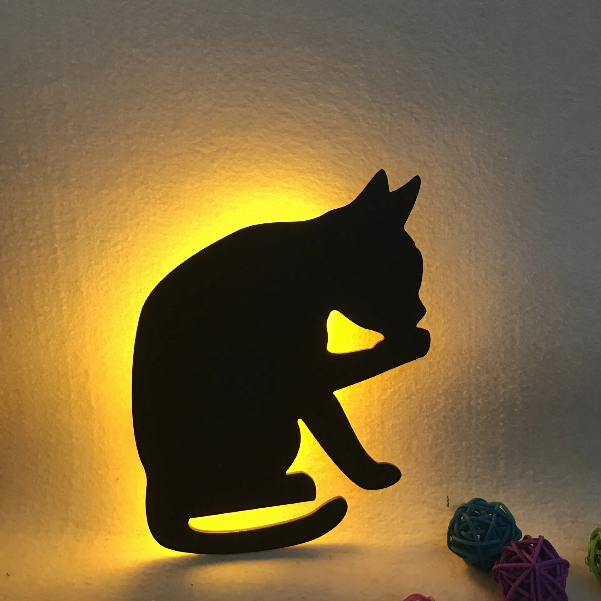 Black cartoon cat shaped LED night light with sound sensor for wall mounting.