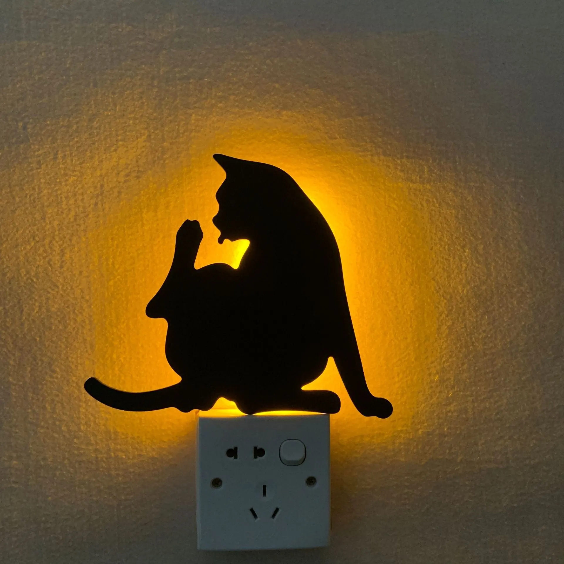 Black cartoon cat shaped LED night light with sound sensor for wall mounting.