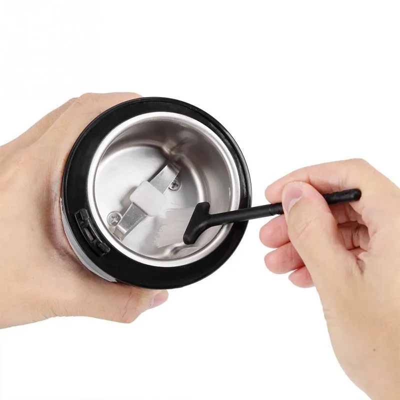 Black or purple mini electric grinder with stainless steel liner on a kitchen worktop