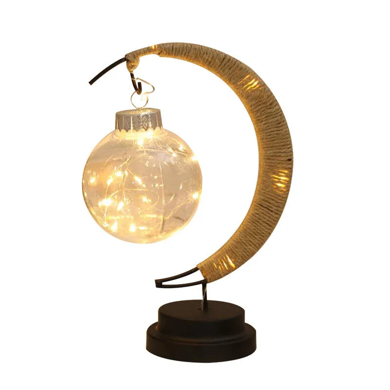 Moon ball shape LED night light with crescent holder, PVC shell, warm light on a wooden table