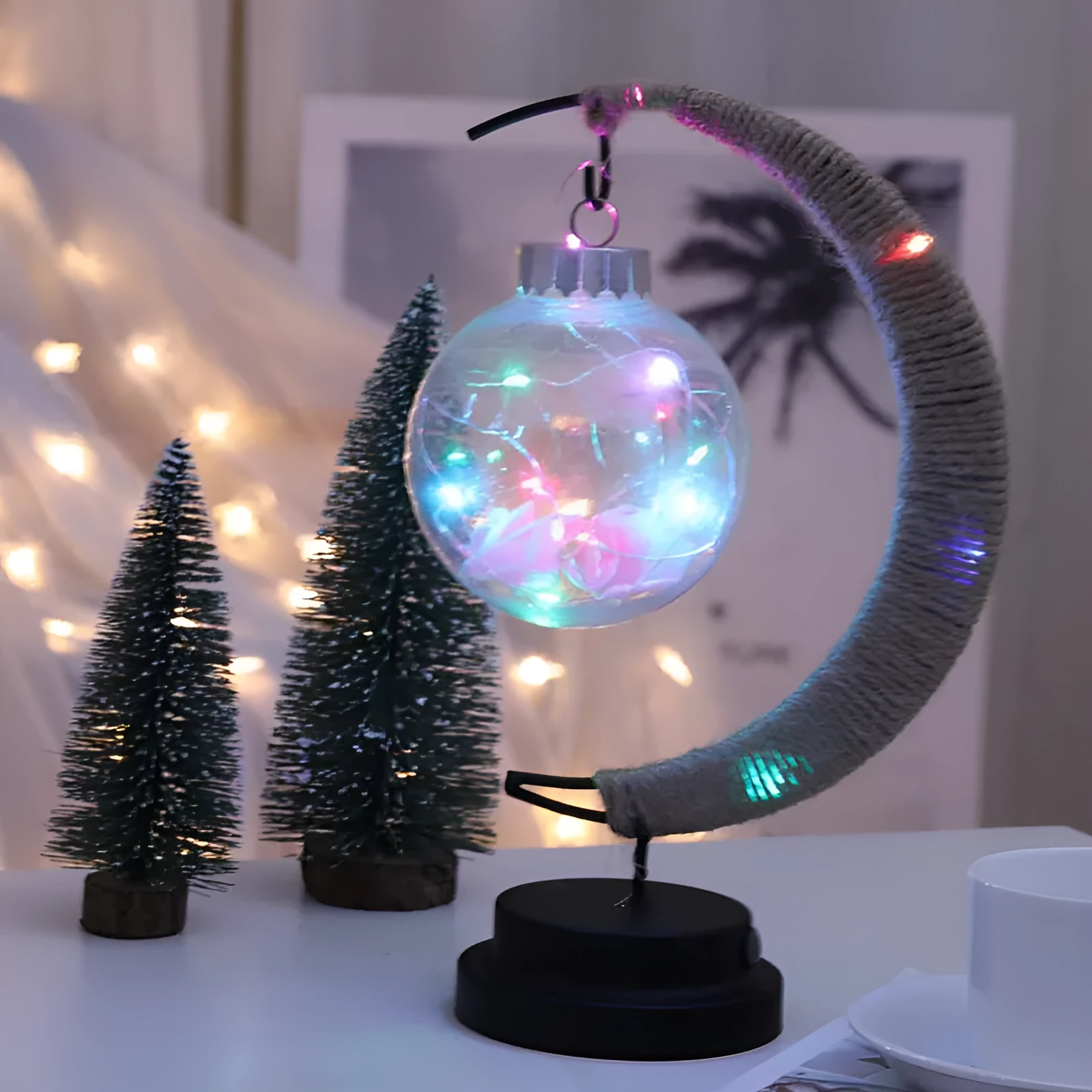 Moon ball shape LED night light with crescent holder, PVC shell, warm light on a wooden table
