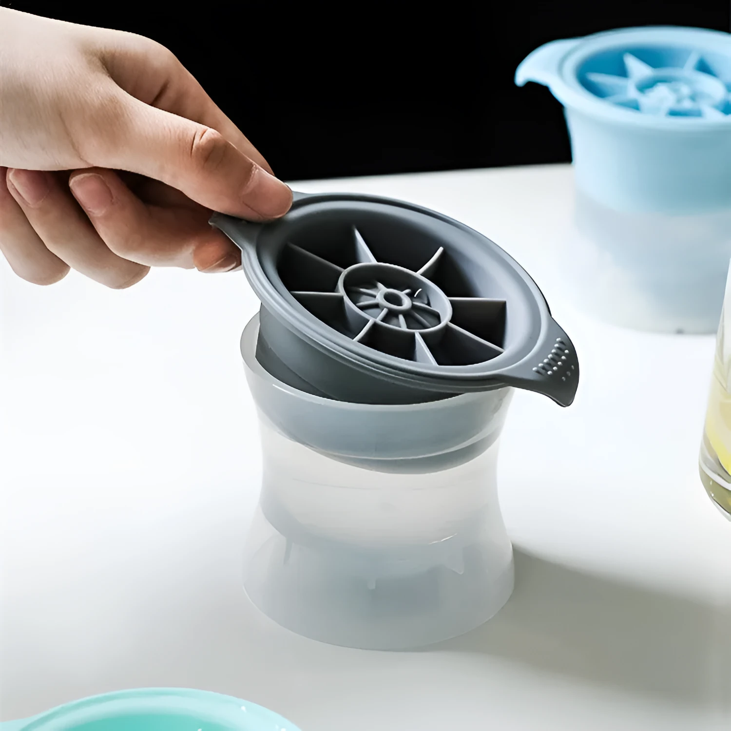 Flexible silicone ice tray showing large ice hockey, pentagon, and spherical mould designs in light blue.