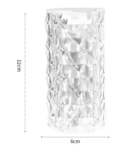 Rose atmosphere crystal bedside lamp with plastic lampshade emitting soft yellow light on a wooden table