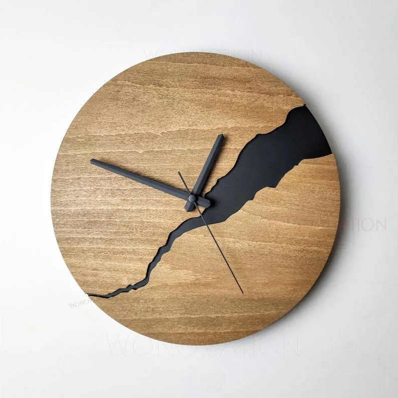 Modern simple wooden wall clock with a crack design dial on a light wood background.