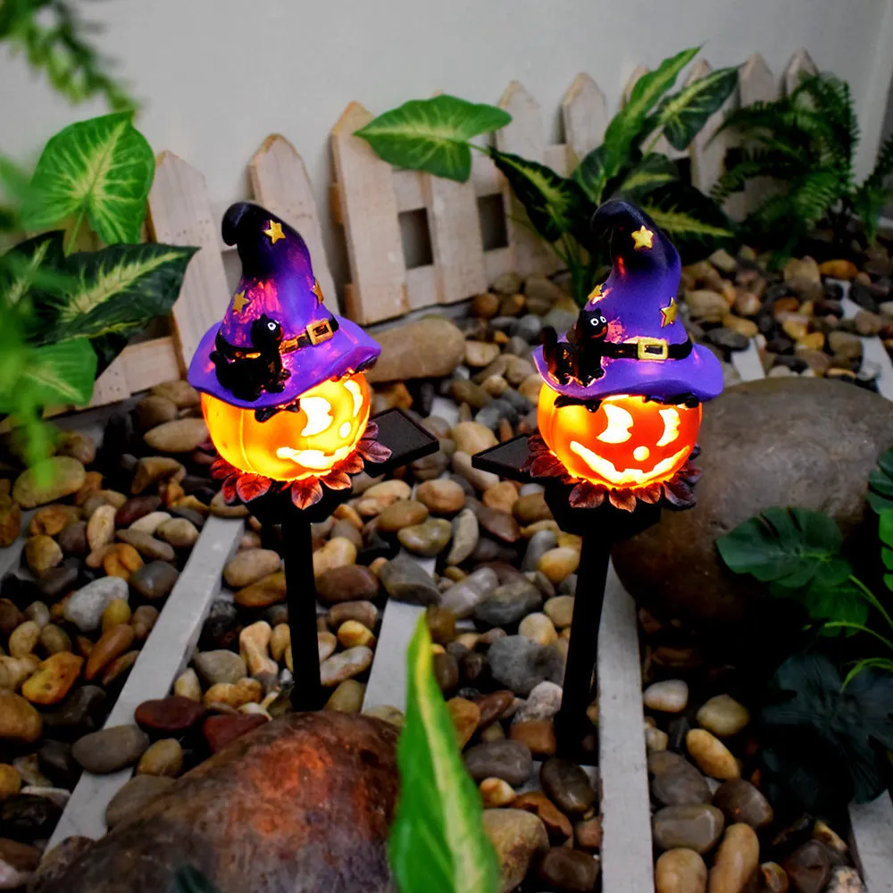 Solar Halloween pumpkin lantern with wizard pumpkin style on a garden path, wrought iron frame