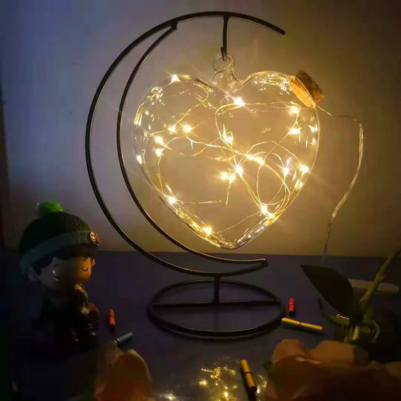 Round glass LED wishing bottle 12 cm with cork, 20 warm white lights, and folded star paper strips on a table