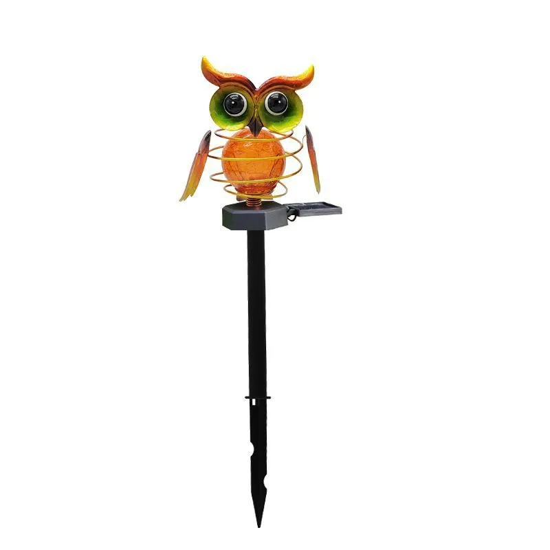 Solar-powered owl lawn lamp with iron sculpture and glass lampshade in a garden setting