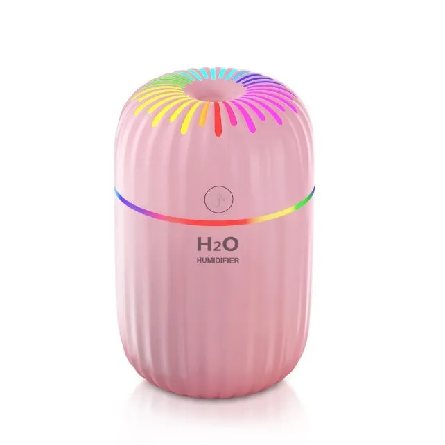 Small white USB desktop humidifier with water tank on a wooden desk.
