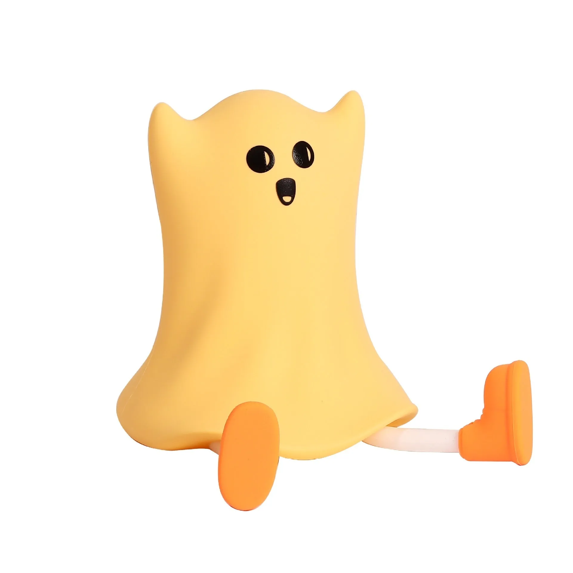 Ghost shaped silicone bedside lamp with touch control emitting soft yellow glow on a bedside table