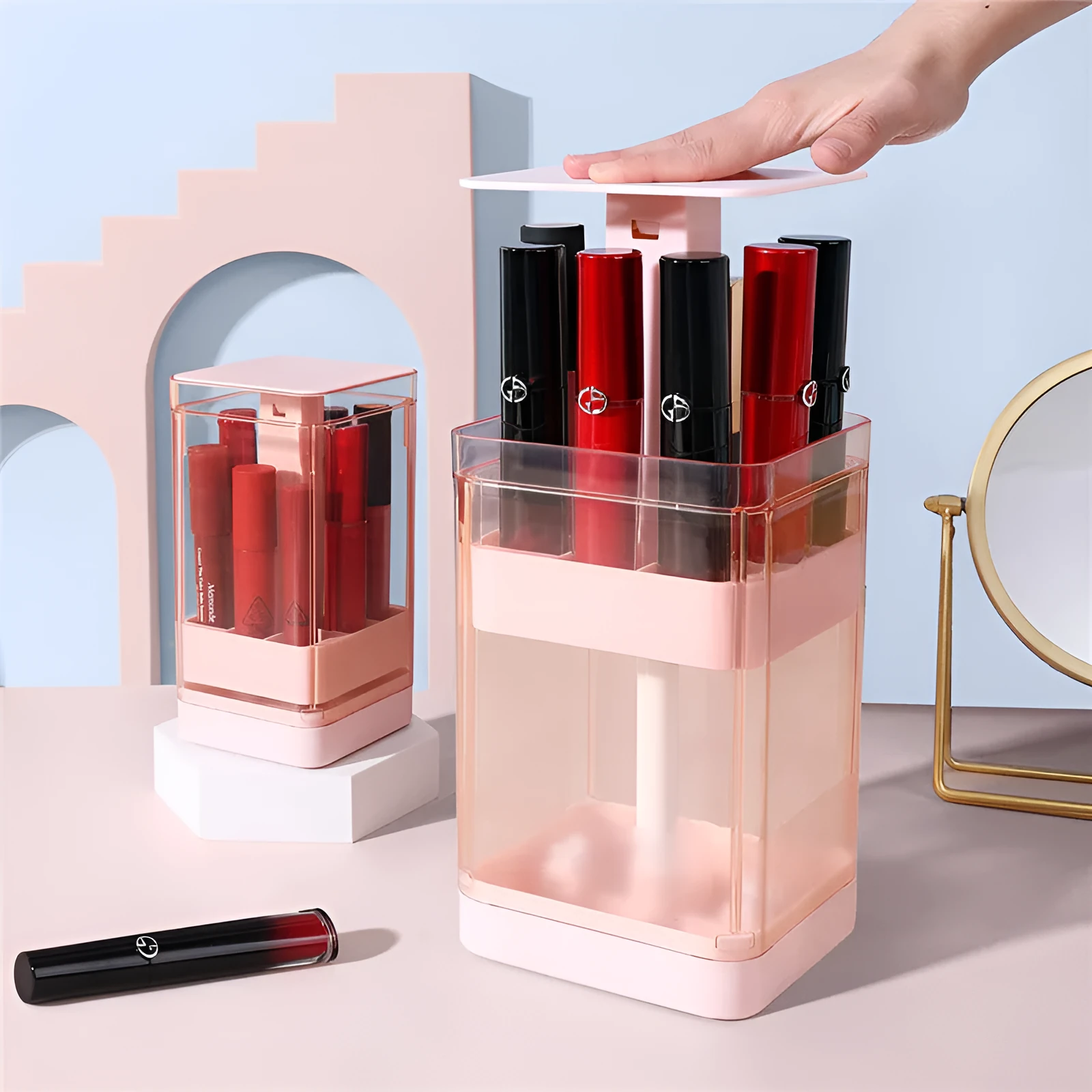 Pink press-lift lipstick storage box with dust cover on a desktop.