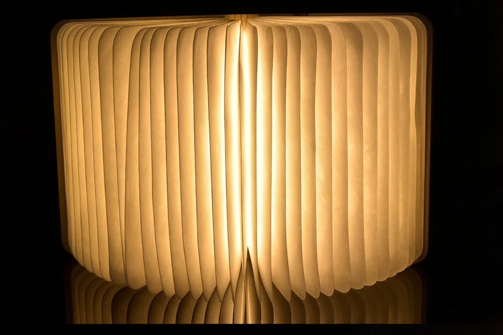 Walnut wooden book light open with colour changing LED pages on a desk