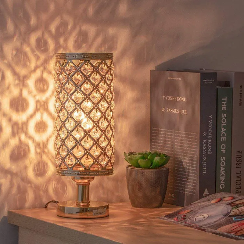 Modern crystal table lamp with hollow-carved design, metal base, gold finish, push button switch, on bedside table