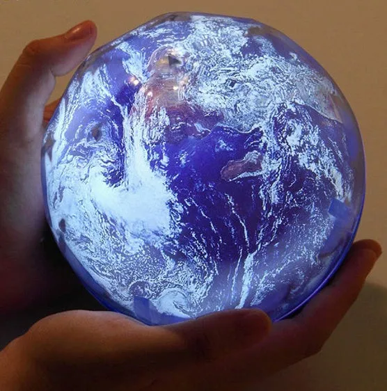 Galaxy projector lamp with diamond-shaped shell showing earth pattern on a table