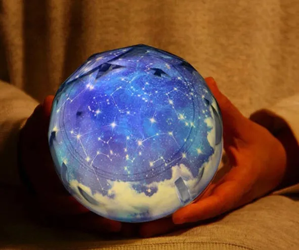 Galaxy projector lamp with diamond-shaped shell showing earth pattern on a table
