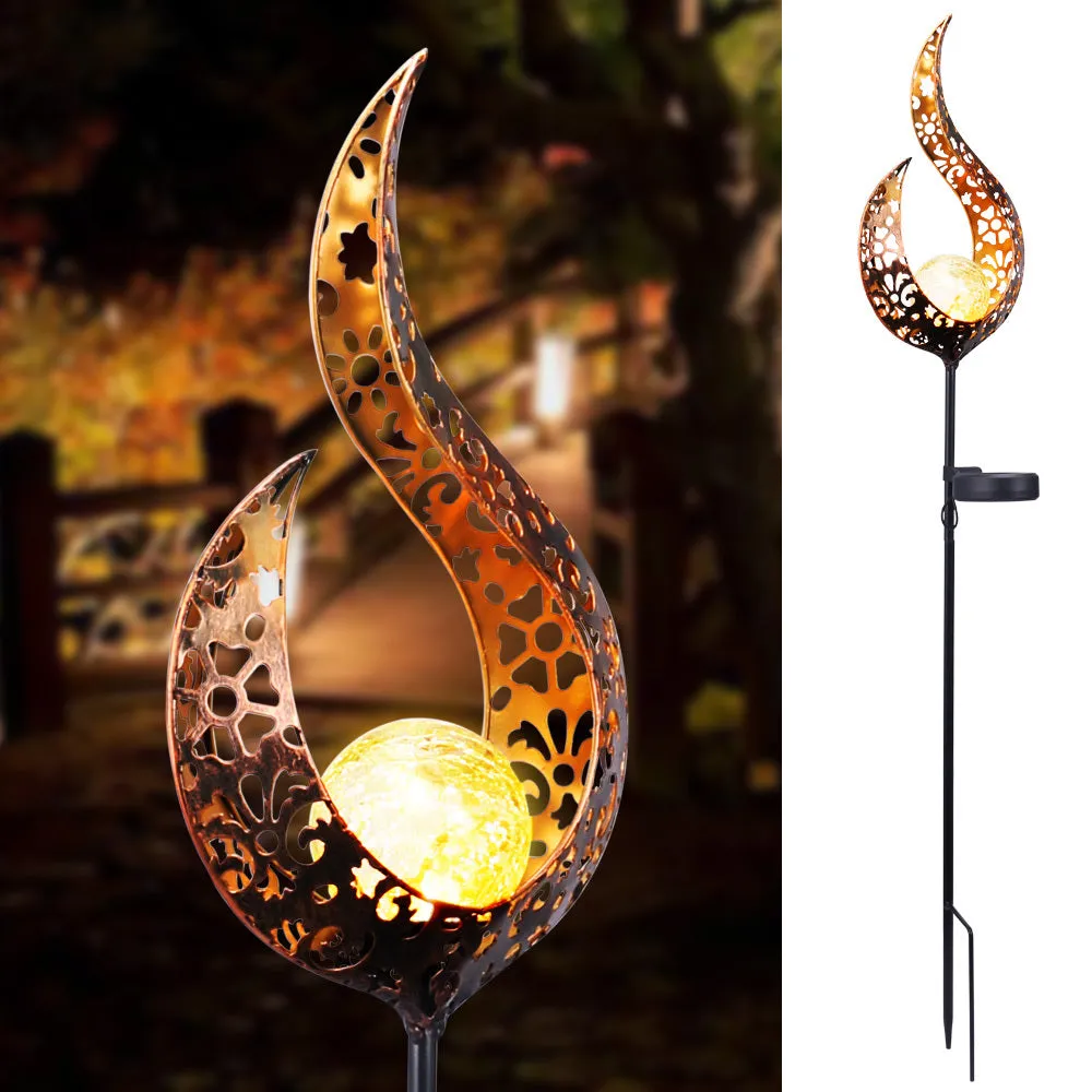 LED solar flame light with warm white glow in a garden, featuring iron and glass construction and stake stand