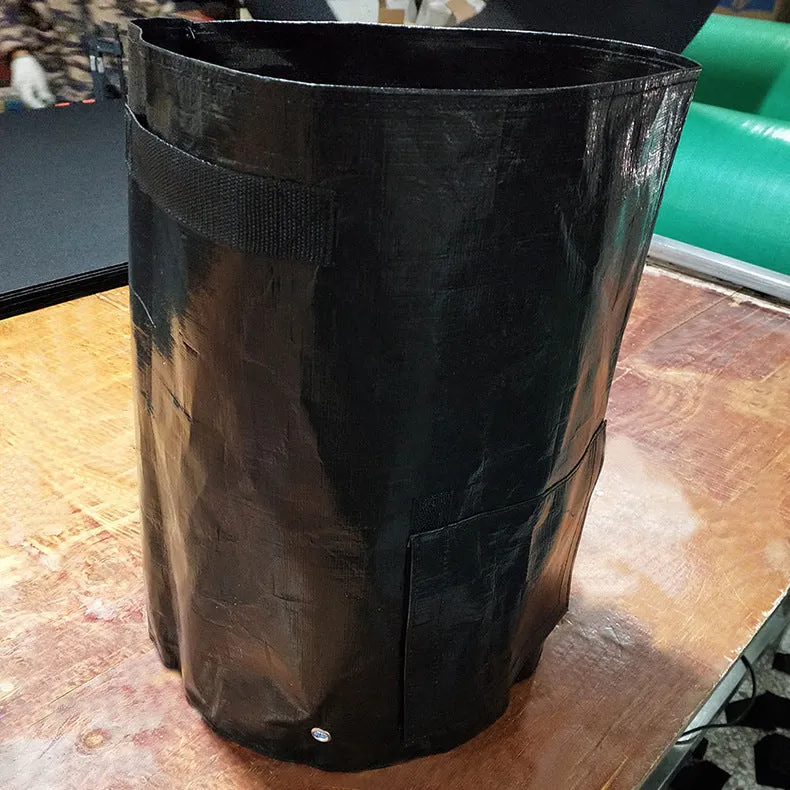 Dark green PE garden planting bag with side windows and double handles on a balcony