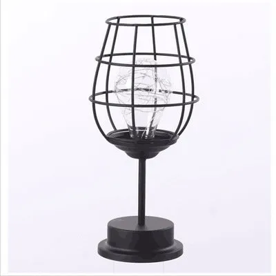 Hollow wrought iron wine bottle shaped table lamp with warm white LED light on a wooden desk