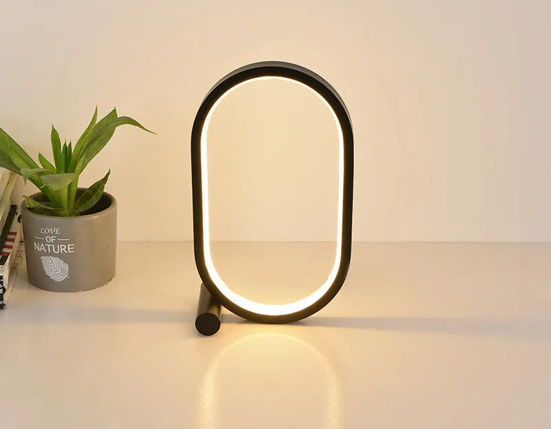 USB plug-in oval acrylic touch dimmable night light with metal base on a desk, black colour