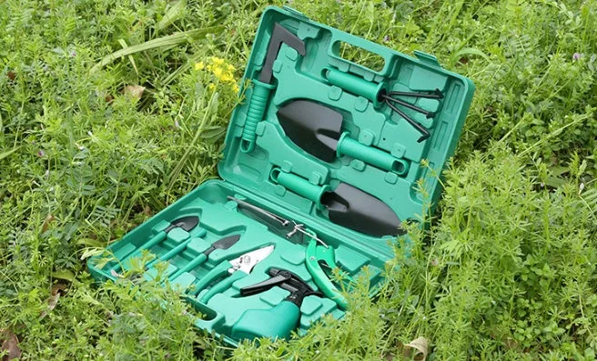 Ten-piece gardening tool set with iron heads and green plastic handles on a wooden background