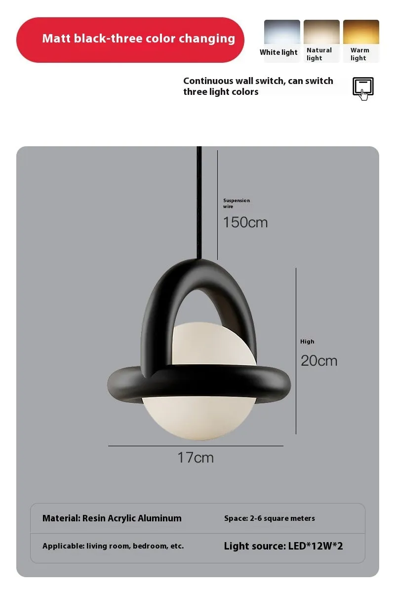Matte black hanging line lamp with a long black cord suspended above a bedside table.