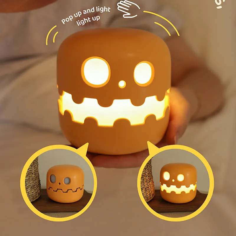 Pumpkin-shaped silicone LED night light in orange and green colour, 102mm by 94mm, with soft glow on a bedside table