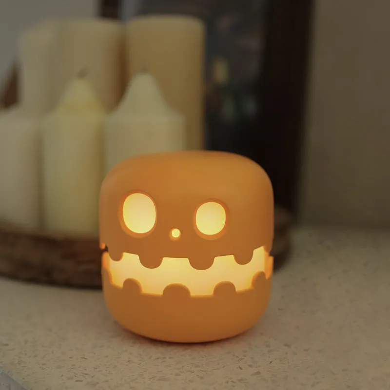 Pumpkin-shaped silicone LED night light in orange and green colour, 102mm by 94mm, with soft glow on a bedside table