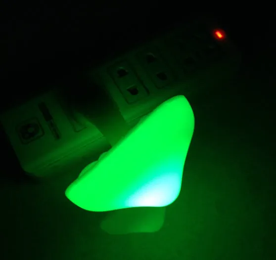 Mushroom-shaped LED night light with light sensor, warm yellow glow, plugging into a wall socket