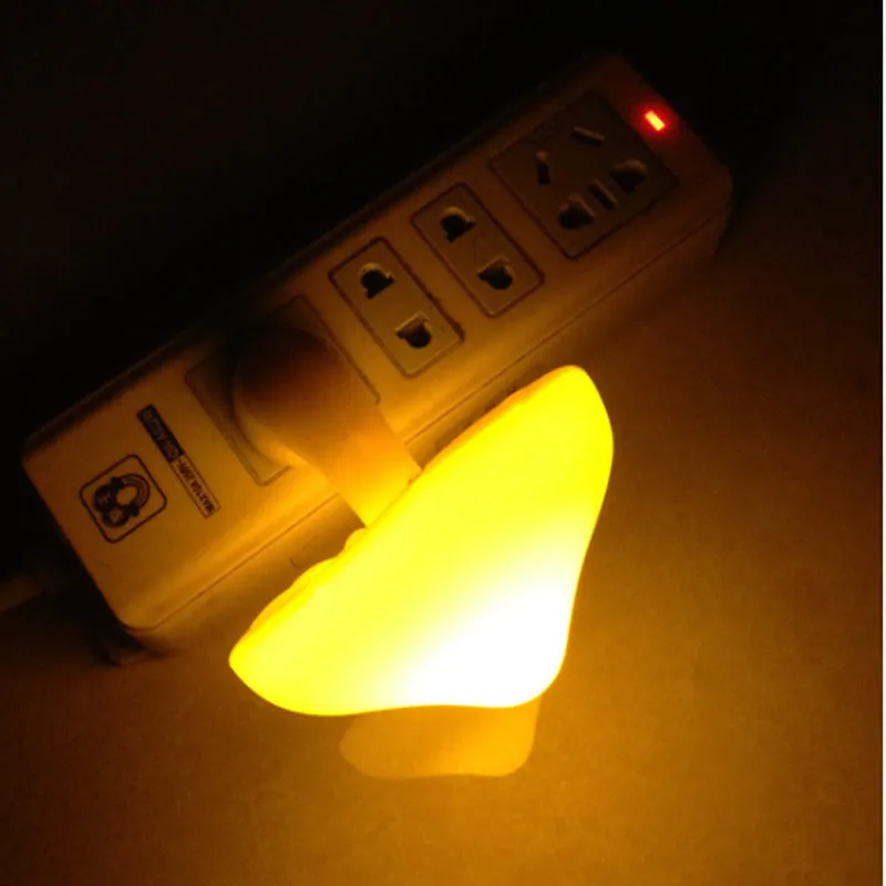 Mushroom-shaped LED night light with light sensor, warm yellow glow, plugging into a wall socket