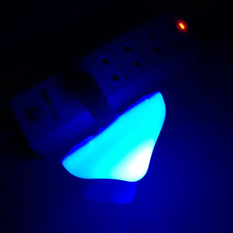 Mushroom-shaped LED night light with light sensor, warm yellow glow, plugging into a wall socket